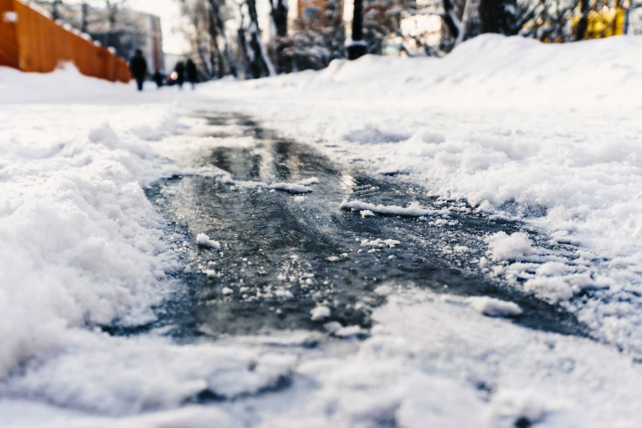 Slippery icy sidewalk in winter under fresh snow