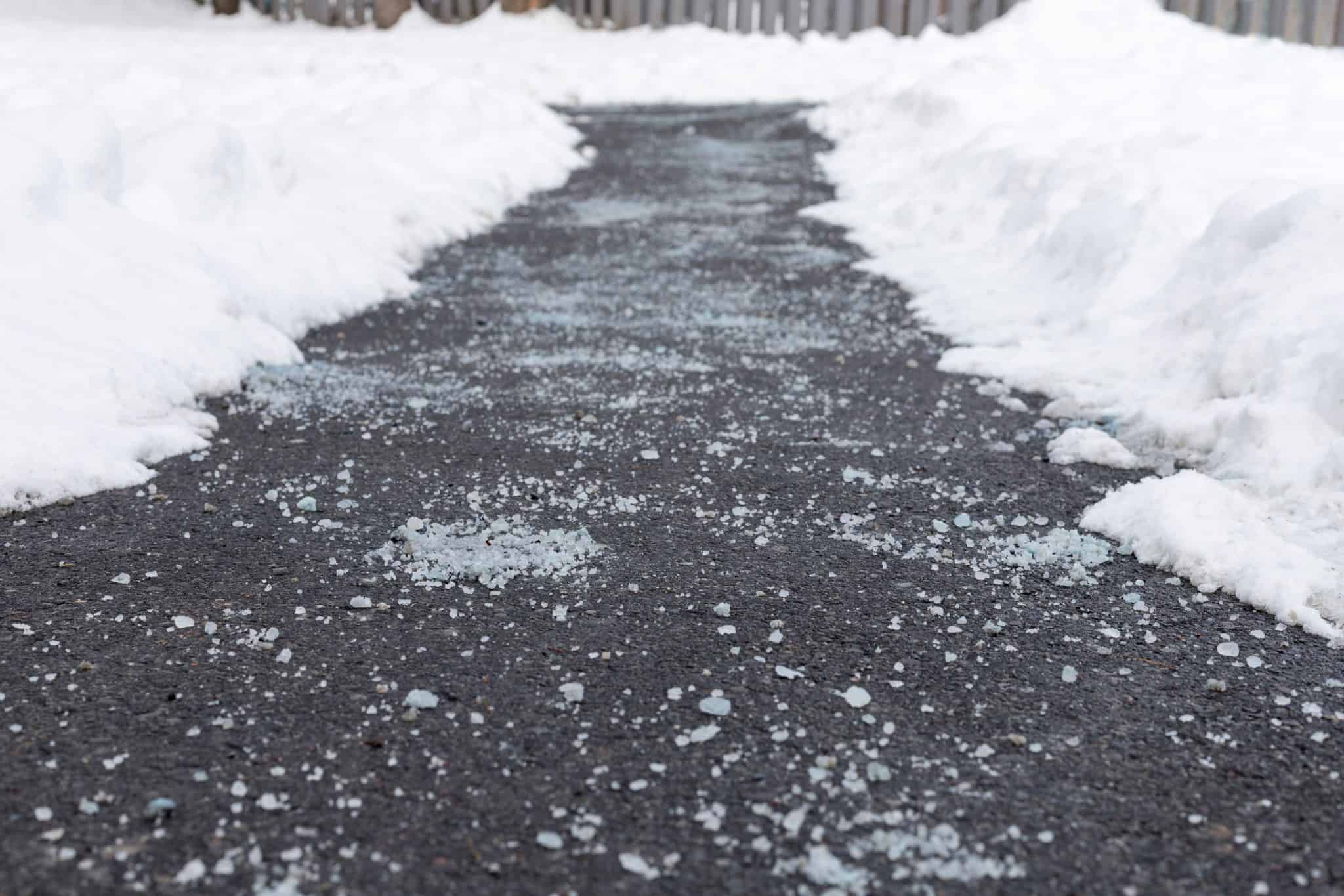 Winter road treated with liquid de-icer for melting snow and ice