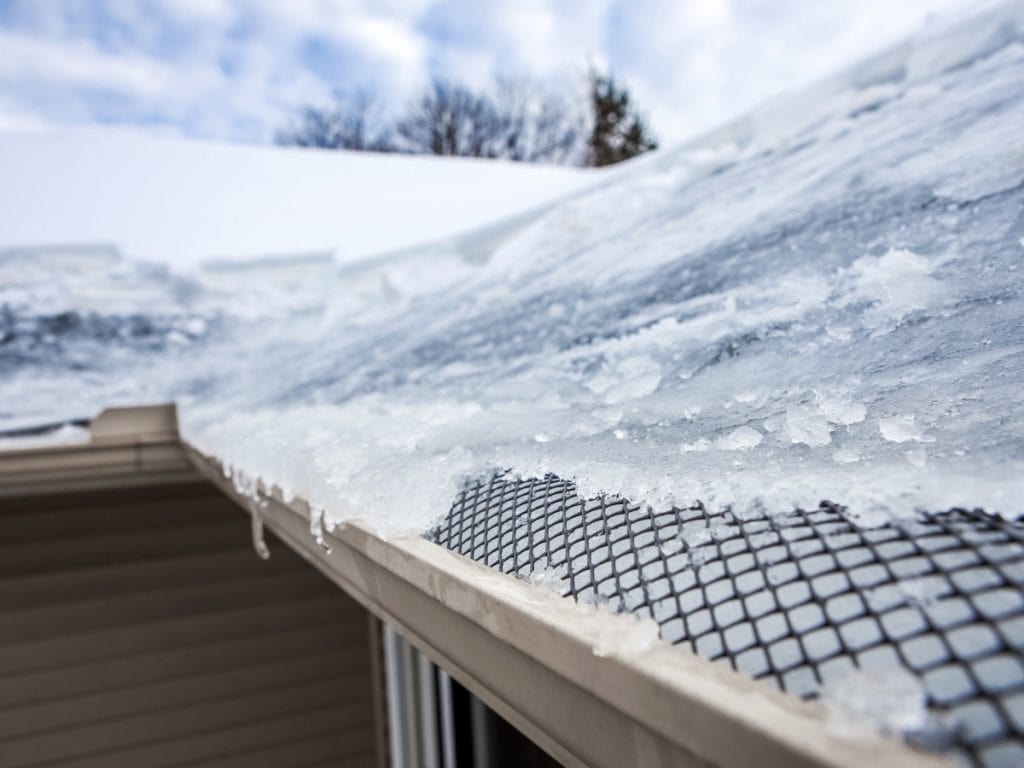 Ice forming along a roof edge above a walkway in winter