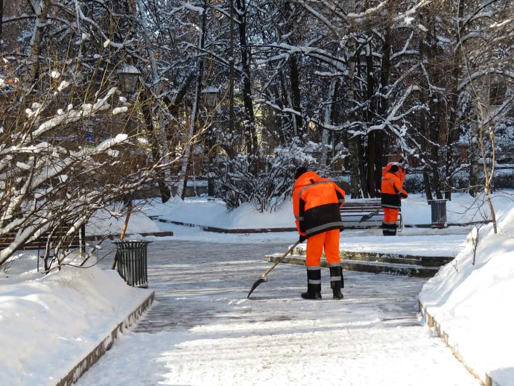 Snow removal crew applying liquid ice melt to pavement